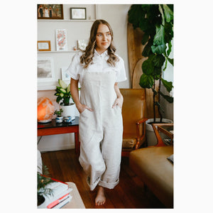 Elle wears a white short sleeve, size 10, paired with a natural Wattlebird Jumpsuit